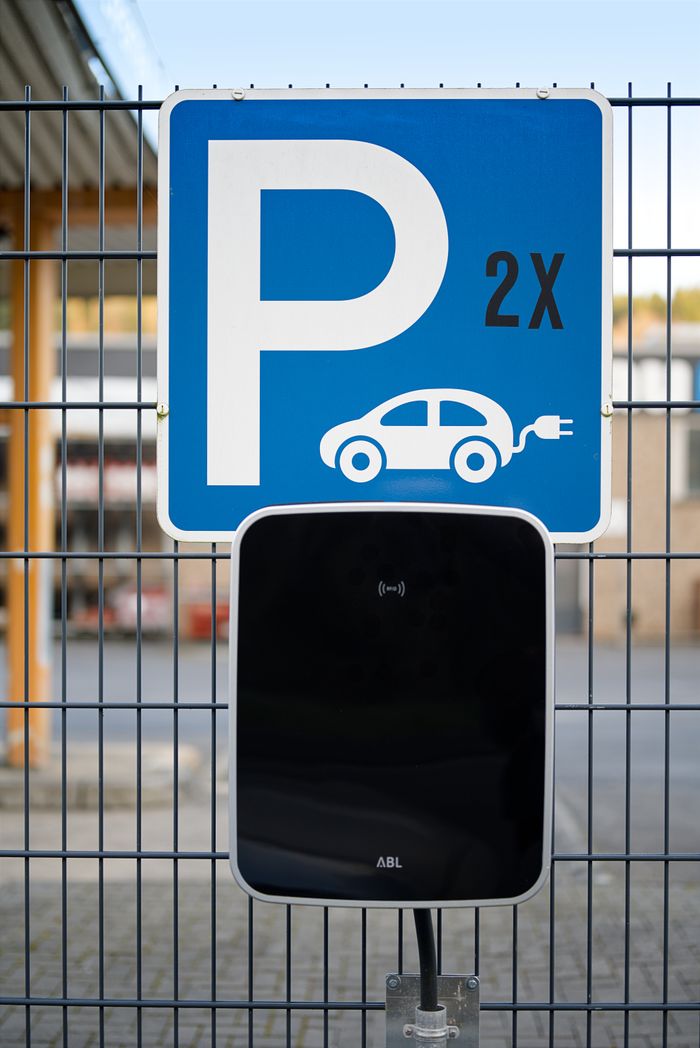 Close-up of electric vehicle parking and charging station sign outdoors.